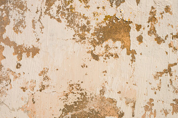 Grunge background of cracked peeling walls with peeled putty in beige tones