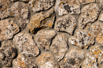 The outer facade of the building is made of natural stone of various shapes. Background texture for outdoor decoration under the Middle Ages