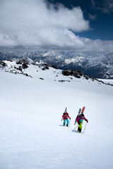 Two young women sportswomen backcountry climbing in the snow high in the mountains for freeride skiing off pistes