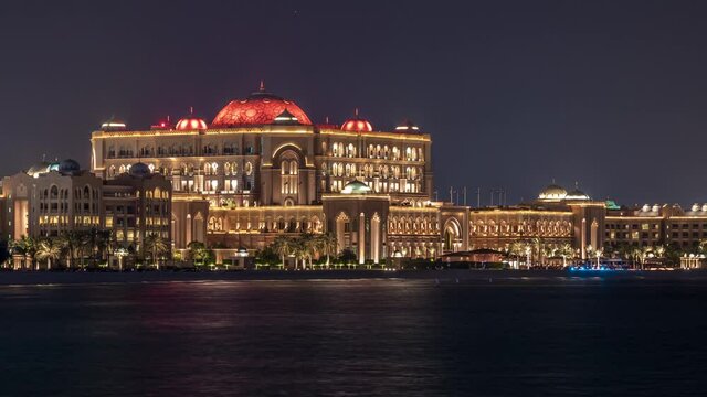 Emirates Palace illuminated at night timelapse, Abu Dhabi, United Arab Emirates. Lights reflected in water