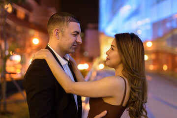Portrait of couple looking each other outdoors at night in the city at Bangkok Thailand