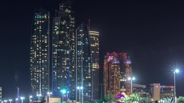 Skyscrapers of Abu Dhabi illuminated at night with Etihad Towers buildings timelapse with glowing windows. United Arab Emirates