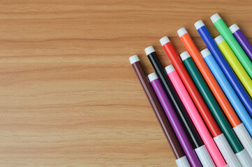 Obraz premium Top view of colorful pen colors over wooden background. Copy space for the text. Education concept.