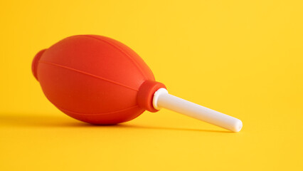 Red hand air blower on yellow background. Clean and camera from dust. Dust remover air blower for digital camera