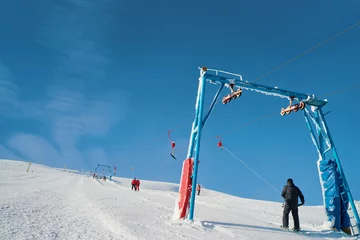 Fotobehang Ski lift going over the snowy mountain and paths from skies and snowboards. © luengo_ua