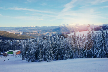 Snowy mountains and ski lifts. Skiers and snowboarders skiing downhill to village.
