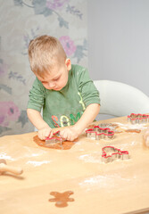 A young boy pushes gingerbread shapes. Getting ready for Christmas.