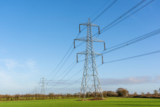 Electricity pylons in a field with blue sky. Bishop's Stortford, Hertfordshire. UK - Powered by Adobe
