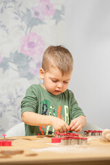 A young boy works at a wooden table, preparing gingerbread.