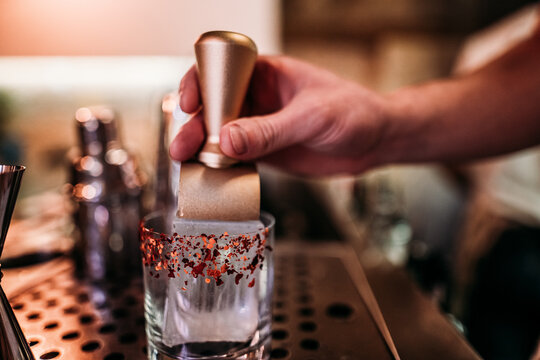 the bartender's hand makes a signet of the name of the bar with his hand on ice for a cocktail