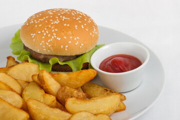 Hamburger with rustic potatoes and ketchup. Serving on a white plate