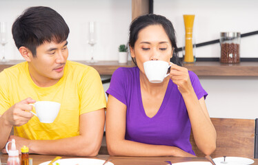 Happy and funny family. Asian lovely couple, beautiful woman and handsome man is having American breakfast, drinking coffee, talking and working together in the kitchen
