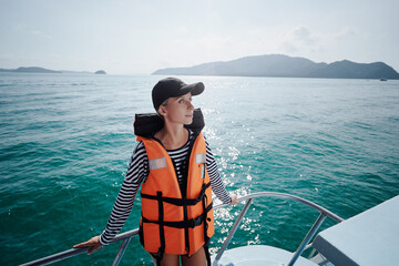Portrait of young woman on the fishing yacht enjoying the seaview.