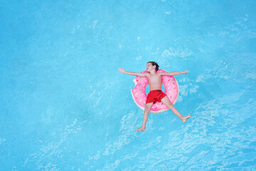 Happy childhood. Top view of happy little boy on the air circle having fun in swimming pool.