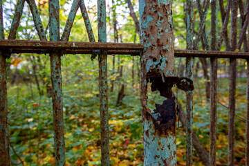 Rust eaten metal pole of old fence around of abandoned garden