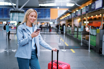 Travel and technology. Online check-in. Female traveler using smartphone waiting for boarding near...
