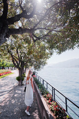 Travel by Italy. Young woman walking on the promenade of Como Lake.