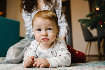 Naklejka premium Mom plays with a little baby boy on the floor. Mother and son. Happy family weekend. Close up.