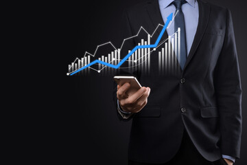 Business man holding holographic graphs and stock market statistics gain profits. Concept of growth planning and business strategy. Display of good economy form digital screen.