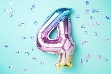 Creative layout. Rainbow foil balloon number and digit four 4. Birthday greeting card. Anniversary concept. Top view. Copy space. Stylish colored numeral over blue background. Numerical digit.