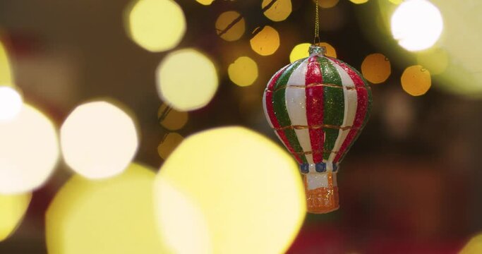 Close up of Christmas tree toy in the form of parachute spinning in light of Christmas lights. Concept of family holidays, perfect Christmas, New Year, celebration.