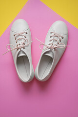 Pair of white gumshoes on colorful background.