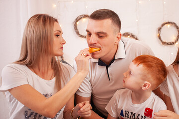 A happy family smiles and Eats sweets. Delicious pies and pastries with cherries, mushrooms. Dad, mom and kids have breakfast, have lunch on the bed.
