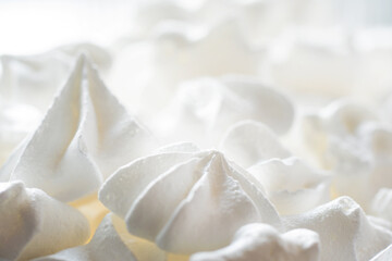Fototapeta na wymiar Blurred sweet crispy twisted meringue, zephyr, marshmallow made from egg whites, sugar and lemon on white food background. Selective focus, shallow depth of field.