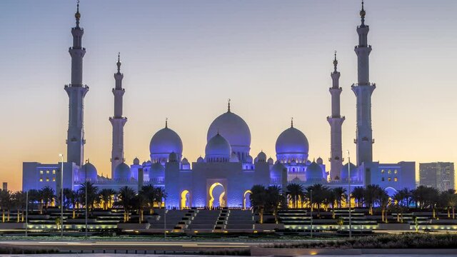 Sheikh Zayed Grand Mosque in Abu Dhabi day to night transition timelapse after sunset, UAE. Evening view from Wahat Al Karama with reflections on water