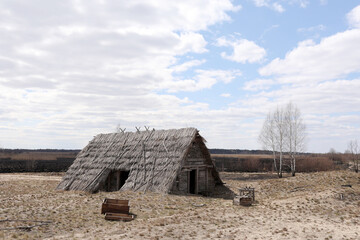 traditional old rustic building with a roof covered with straw on early spring day, Ukraine. tourist place.