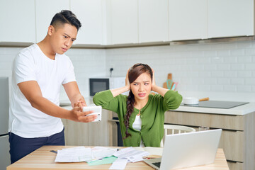 Desperate young couple with many debts reviewing their bills. Financial family problems concept.