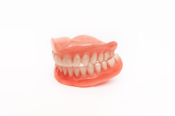 Full removable plastic denture of the jaws. Set of dentures on a white background. A side view of a dental prosthesis, isolate. Two acrylic dentures. Dentures or false teeth, close-up. Copy space