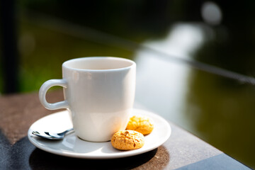 Close up white cup and saucer with ameretti biscuits.