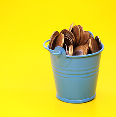 Bucket with coins on a yellow background. Ukrainian money.