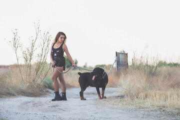 Modelo posando para una sesión en el campo con cadenas y un perro