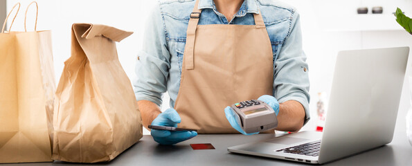 delivery man in a protective mask and gloves holds pos terminal in hand. Service quarantine pandemic coronavirus virus concept