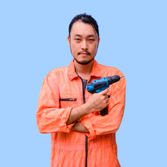 Portrait of handyman in uniform standing and holding cordless screwdriver isolated on blue background.