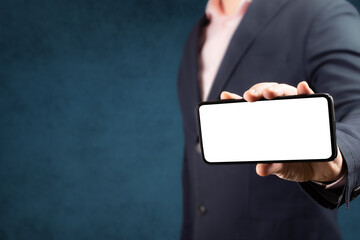 Businessman shows cell phone with blank screen in vertical position. Mock up cell mobile smart phone.
