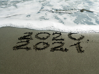 2020 and 2021 written on beach sand  