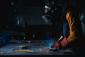 Working tools near welder in welding mask at work in workshop 