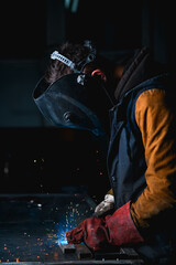 Obraz na płótnie Canvas Welder in mask with visor working in metal on workbanch in factory 