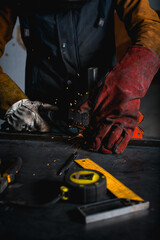 Welder working with semi-automatic electric welding and metal profile near tools in workshop 