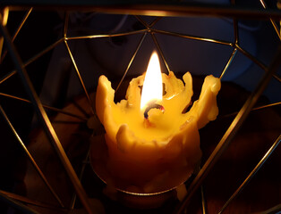 Burning wax candle in modern style metal candlestick.