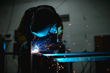 Welder in protective mask working with flashing metal construction and semi-automatic electric...