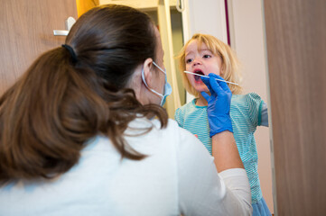 Blonde girl having oropharyngeal swab inserted for covid 19 detection.