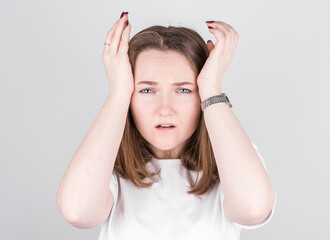 Young woman with a headache holds her temples with her hands. Health, migraine and headache concept.