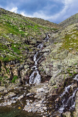 stream cascades flowing over the rocks in the mountains