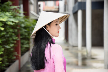 Happy smiling Vietnamese girl; portrait of exotic asian Vietnam woman in traditional Vietnamese Ao Dai dress