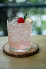 Pink cocktail with lychee syrup and sparkling soda decoration with rosemary cherries and slice lemon
