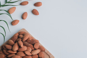The almonds are on a wooden slab and all are placed on a white background.